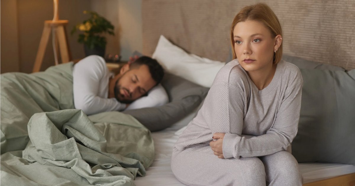 An Indian couple sitting on a bed talking to each other honestly, demonstrating healthy communication to resolve marital bedroom problems.